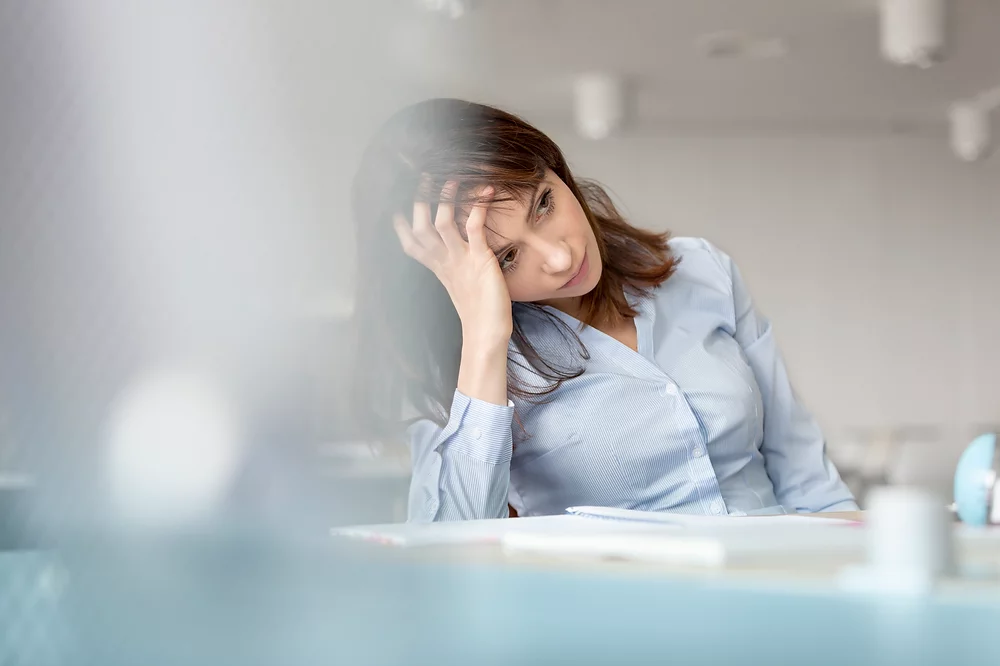A thoughtful professional woman in an office setting, enhancing productivity with Elevate Your Organization's Culture and Performance With CEEK.