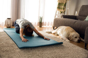 Yoga exercise with a relaxed dog at home, only available at Elevate Your Organization's Culture and Performance With CEEK.