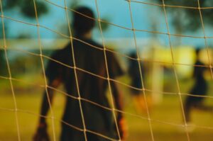 Soccer player behind net on a field, symbolizing teamwork and focus, only available at Elevate Your Organization's Culture and Performance With CEEK.