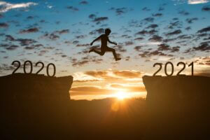 Silhouette jumping from 2020 to 2021 over a canyon at sunrise, symbolizing progress, available at Elevate Your Organization's Culture and Performance With CEEK.