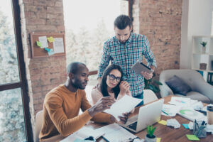 Collaborative team discussion with laptops and tablets, enhancing workplace culture at Elevate Your Organization's Culture and Performance With CEEK.