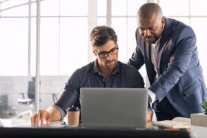 Leadership mentoring an employee at a laptop, enhancing team performance, only at Elevate Your Organization's Culture and Performance With CEEK.