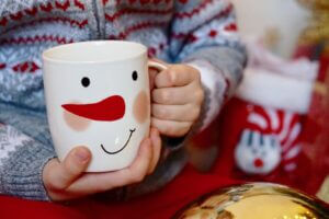 Festive mug with snowman design held by child, enhancing holiday spirit, available at Elevate Your Organization's Culture and Performance With CEEK.