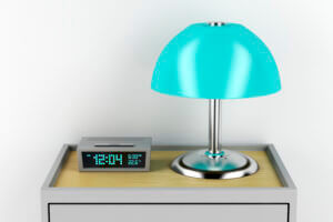 Nightstand with alarm clock and turquoise lamp, available at Elevate Your Organization's Culture and Performance With CEEK.