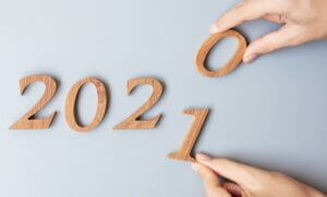 Businessman changing wooden numbers from 2020 to 2021, symbolizing new goals and strategies, only at Elevate Your Organization's Culture and Performance With CEEK.