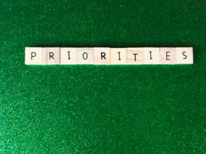 Wooden blocks spelling 'PRIORITIES' on a green background, highlighting focus, only available at Elevate Your Organization's Culture and Performance With CEEK.