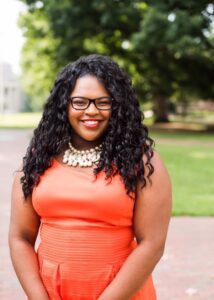 Person smiling outdoors in a vibrant orange outfit, embodying positivity and culture enhancement, available at Elevate Your Organization's Culture and Performance With CEEK.
