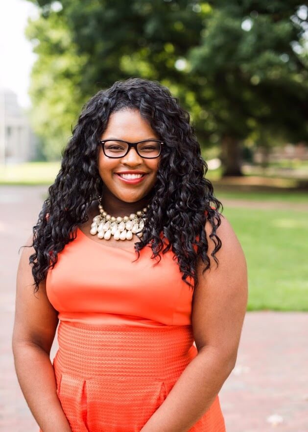 Person smiling outdoors in a vibrant orange outfit, embodying positivity and culture enhancement, available at Elevate Your Organization's Culture and Performance With CEEK.