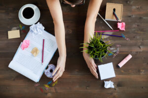 Woman organizing office desk with coffee and plant, enhancing productivity, available at Elevate Your Organization's Culture and Performance With CEEK.