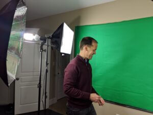 Man setting up a professional green screen studio with lighting, only available at Elevate Your Organization's Culture and Performance With CEEK.