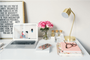 Stylish workspace with laptop, flowers, and gold lamp, perfect for productivity, available at Elevate Your Organization's Culture and Performance With CEEK.