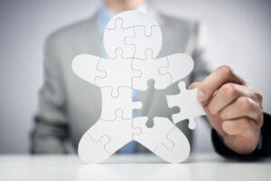 Businessman assembling team jigsaw puzzle, symbolizing collaboration, only at Elevate Your Organization's Culture and Performance With CEEK.