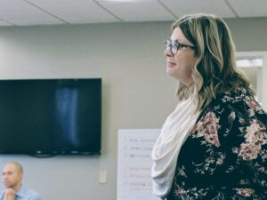 Woman presenting in a meeting room, showcasing leadership and collaboration, only available at Elevate Your Organization's Culture and Performance With CEEK.