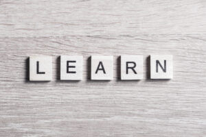 Wooden tiles spelling "LEARN" on a textured surface, featured at Elevate Your Organization's Culture and Performance With CEEK.