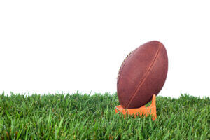 American football ready for kickoff on grass, showcasing team spirit, only at Elevate Your Organization's Culture and Performance With CEEK.
