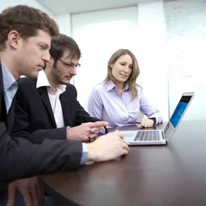 Team collaboration around a laptop in an office setting, showcasing Elevate Your Organization's Culture and Performance With CEEK expertise.