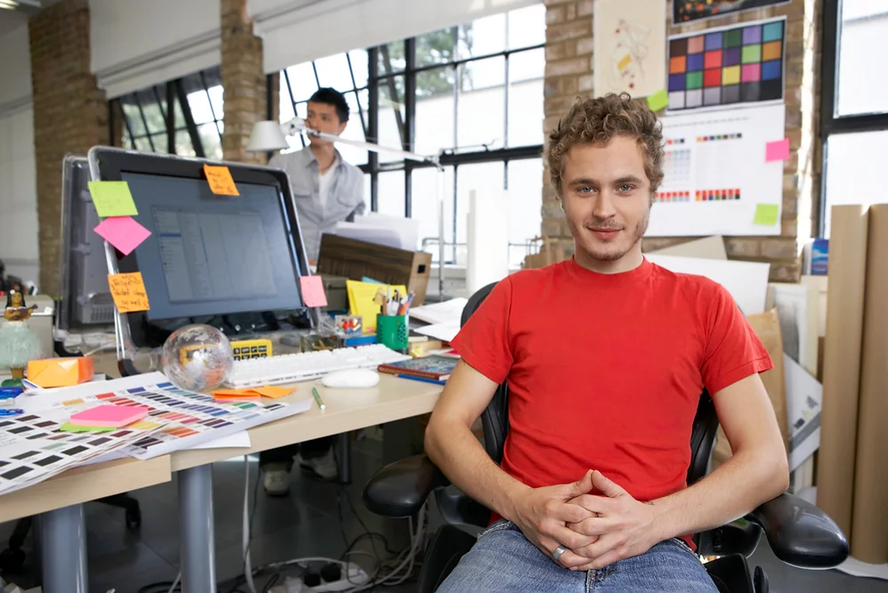 Creative workspace with a designer in a red shirt, emphasizing teamwork and innovation, only available at Elevate Your Organization's Culture and Performance With CEEK.