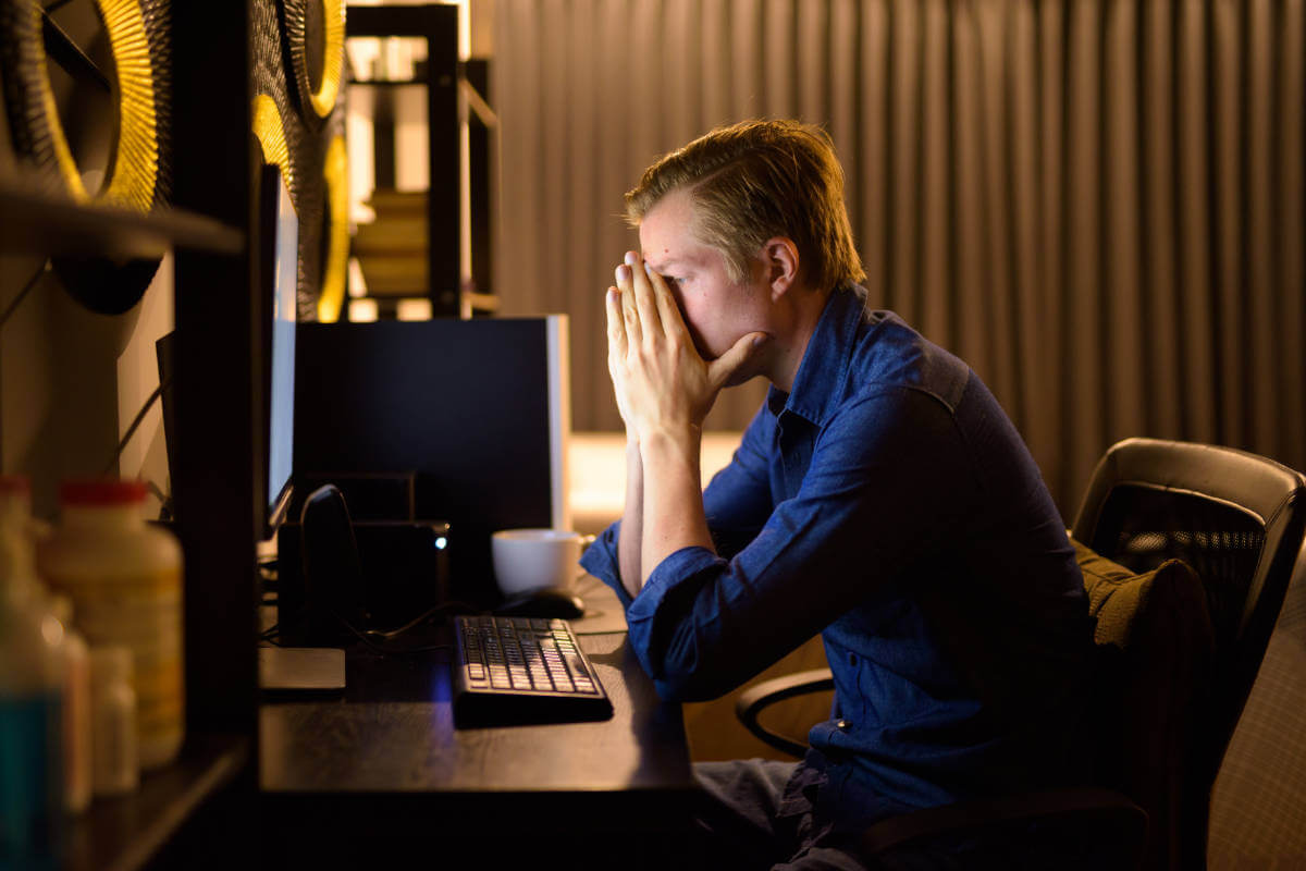 Stressed young businessman working late, showcasing work-life balance solutions at Elevate Your Organization's Culture and Performance With CEEK.