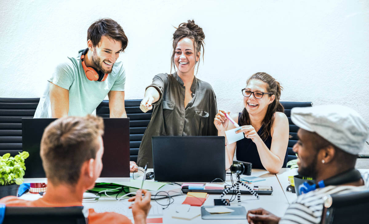 Young employees collaborating at a computer in a startup setting, only available at Elevate Your Organization's Culture and Performance With CEEK.