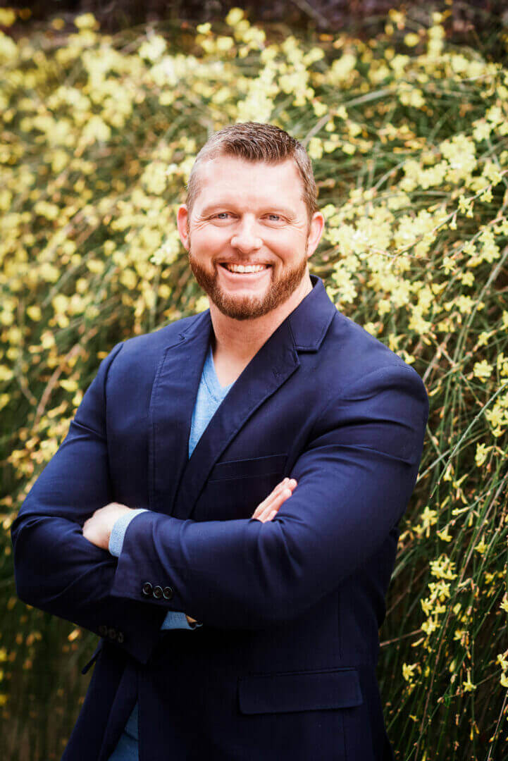 Confident man in a blue blazer smiling in nature, only available at Elevate Your Organization's Culture and Performance With CEEK.