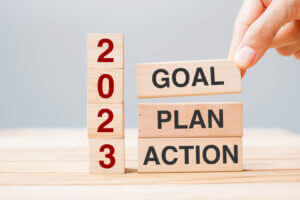 Hand holding wooden blocks with '2023 GOAL PLAN ACTION', only at Elevate Your Organization's Culture and Performance With CEEK.