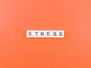 Stress management concept with Scrabble tiles on orange background, featured by Elevate Your Organization's Culture and Performance With CEEK.