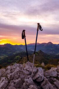 Trekking poles on rocky terrain with a scenic sunset, only available at Elevate Your Organization's Culture and Performance With CEEK.