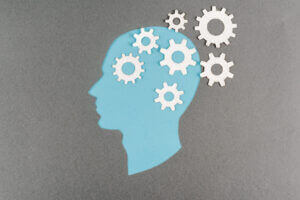 Top view of a blue human head with white gears on grey, symbolizing innovation, only at Elevate Your Organization's Culture and Performance With CEEK.