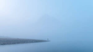 Traveler man standing alone in blue fog with rocky mountains by
